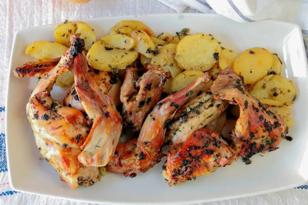 Delicioso conejo al horno con patatas doradas y hierbas arom&aacute;ticas, un plato casero que huele a tradici&oacute;n.