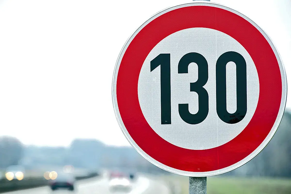 Verkehrsschild zeigt 130 km/h, die höchstgeschwindigkeit portugal. Autos fahren auf einer nassen Straße im Hintergrund.