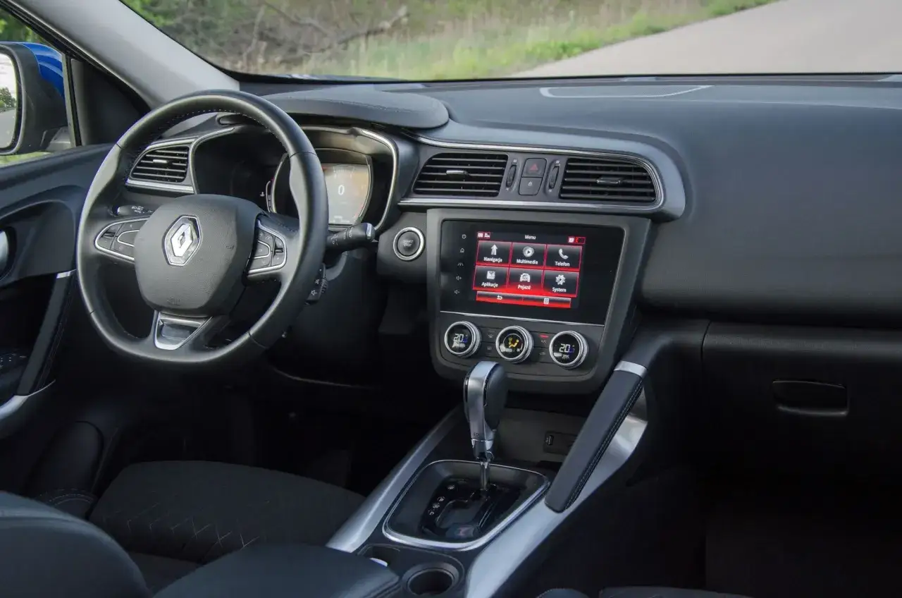 Wnętrze Renault Kadjar. Widok na deskę rozdzielczą, kierownicę i ekran multimediów. Wady tego modelu mogą dotyczyć np. ergonomii.