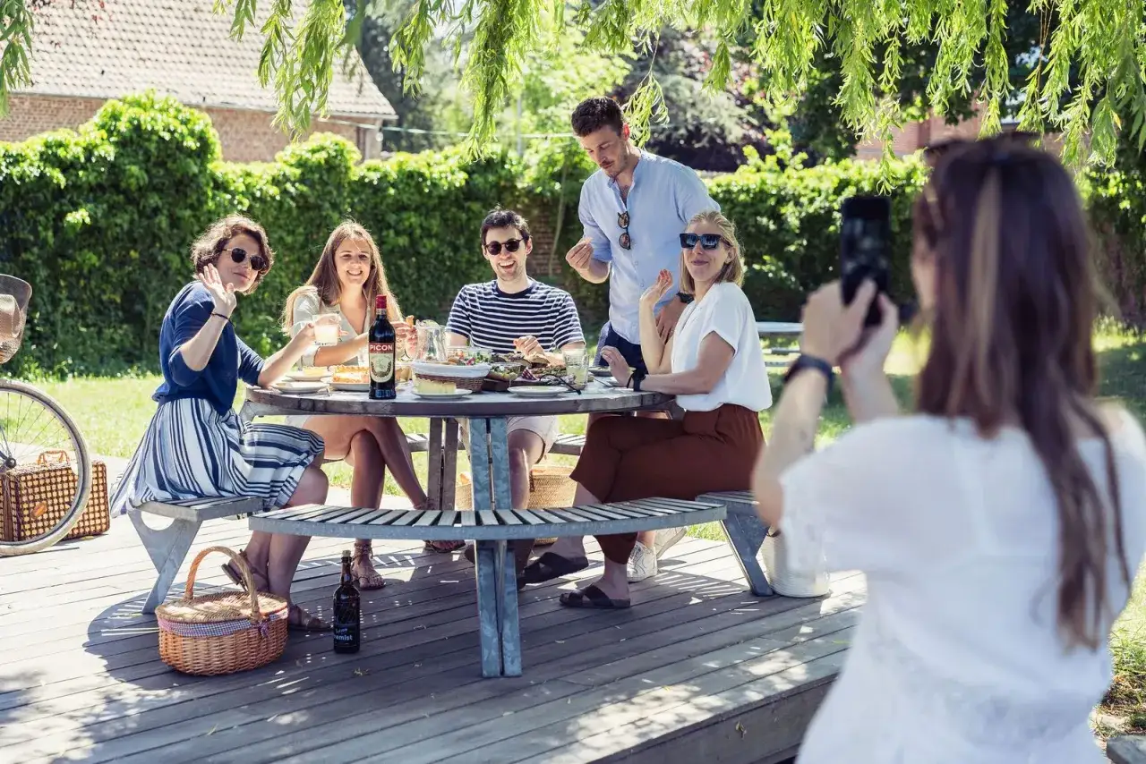 Amis profitent d'un pique-nique ensoleillé. Idées de que prendre pour un picnic entre amis : salades, bouteille de Picon, et bonne humeur.