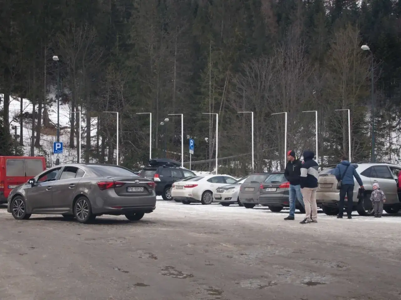 Zimowy parking w Kuźnicach. Kilka samochodów, ludzie czekają. Ciekawe, ile kosztuje parking w Kuźnicach?