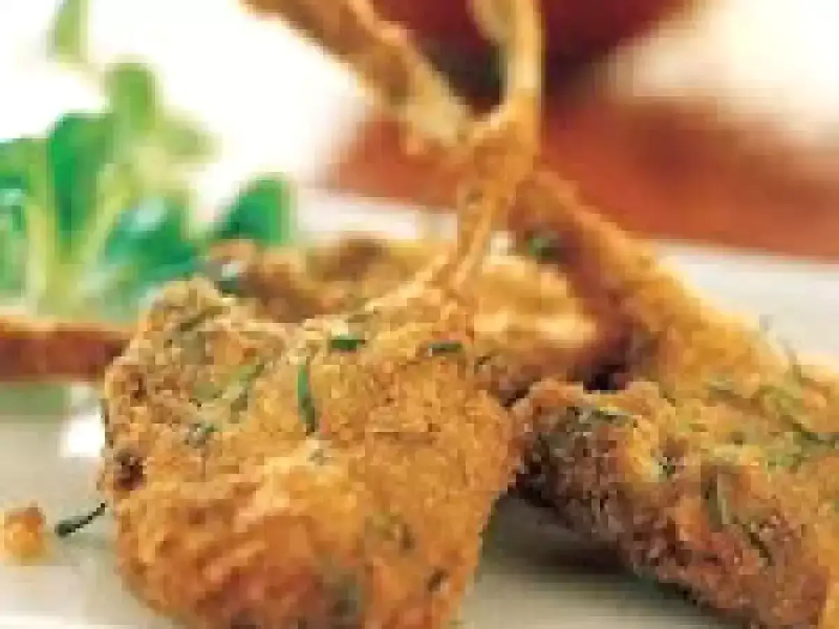 Costolette di agnello in padella, dorate e croccanti, servite con un contorno di insalata fresca.
