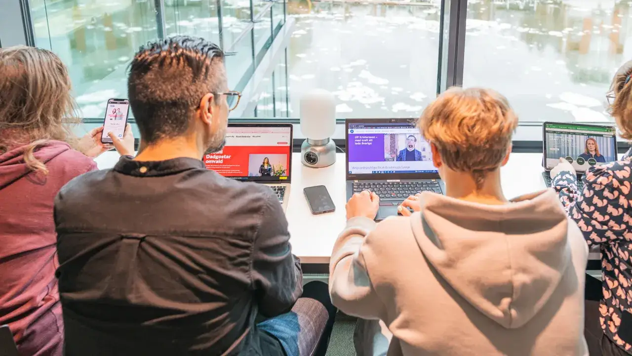 Fyra personer vid datorer och en mobil. En skärm visar en politisk debatt, en annan en intervju med Ulf Kristersson. En diskussion om politiska frågor, en polemik synonym.