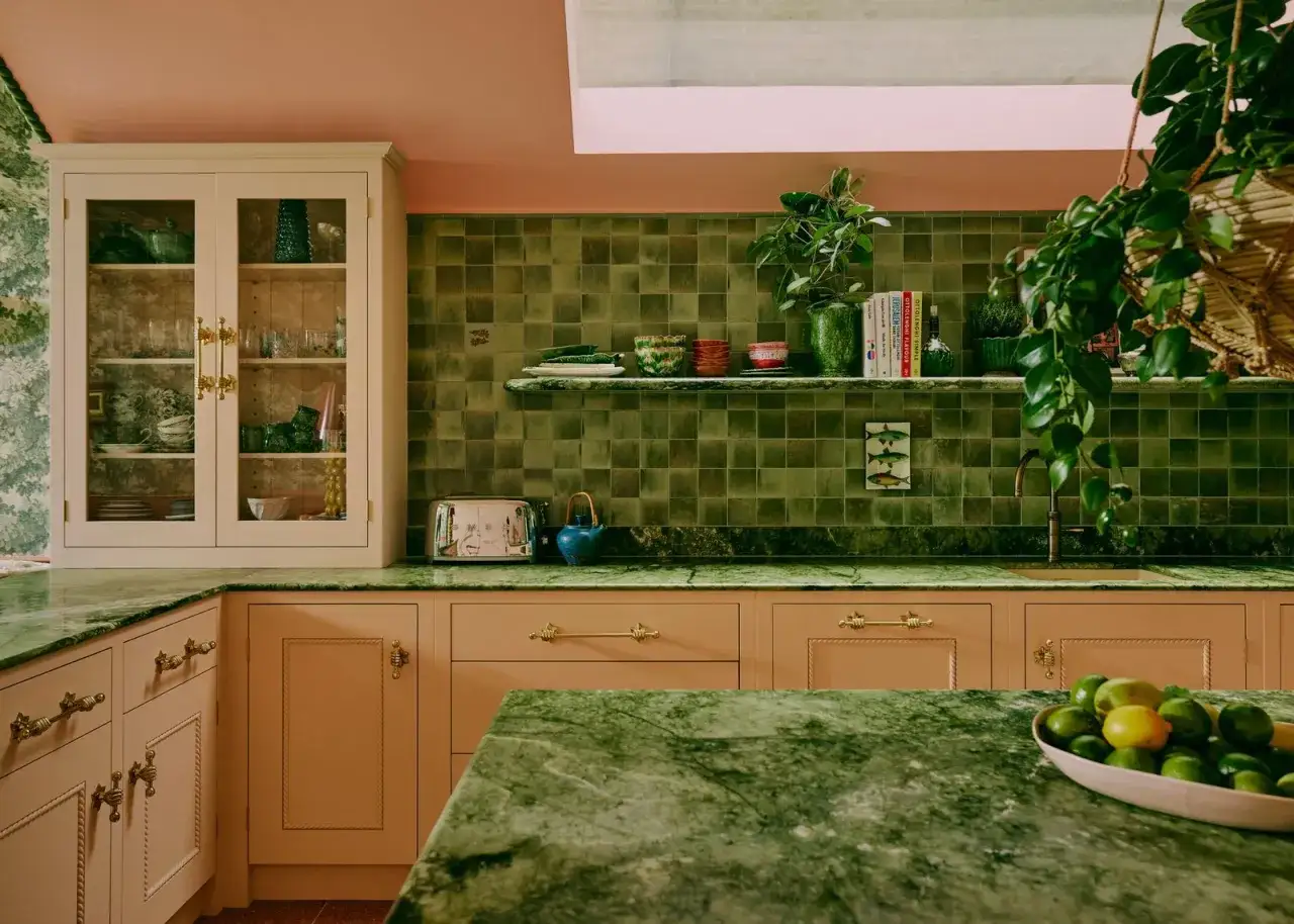 Cocinas verdes vintage con encimeras de mármol, armarios color melocotón y azulejos de pared verde musgo.