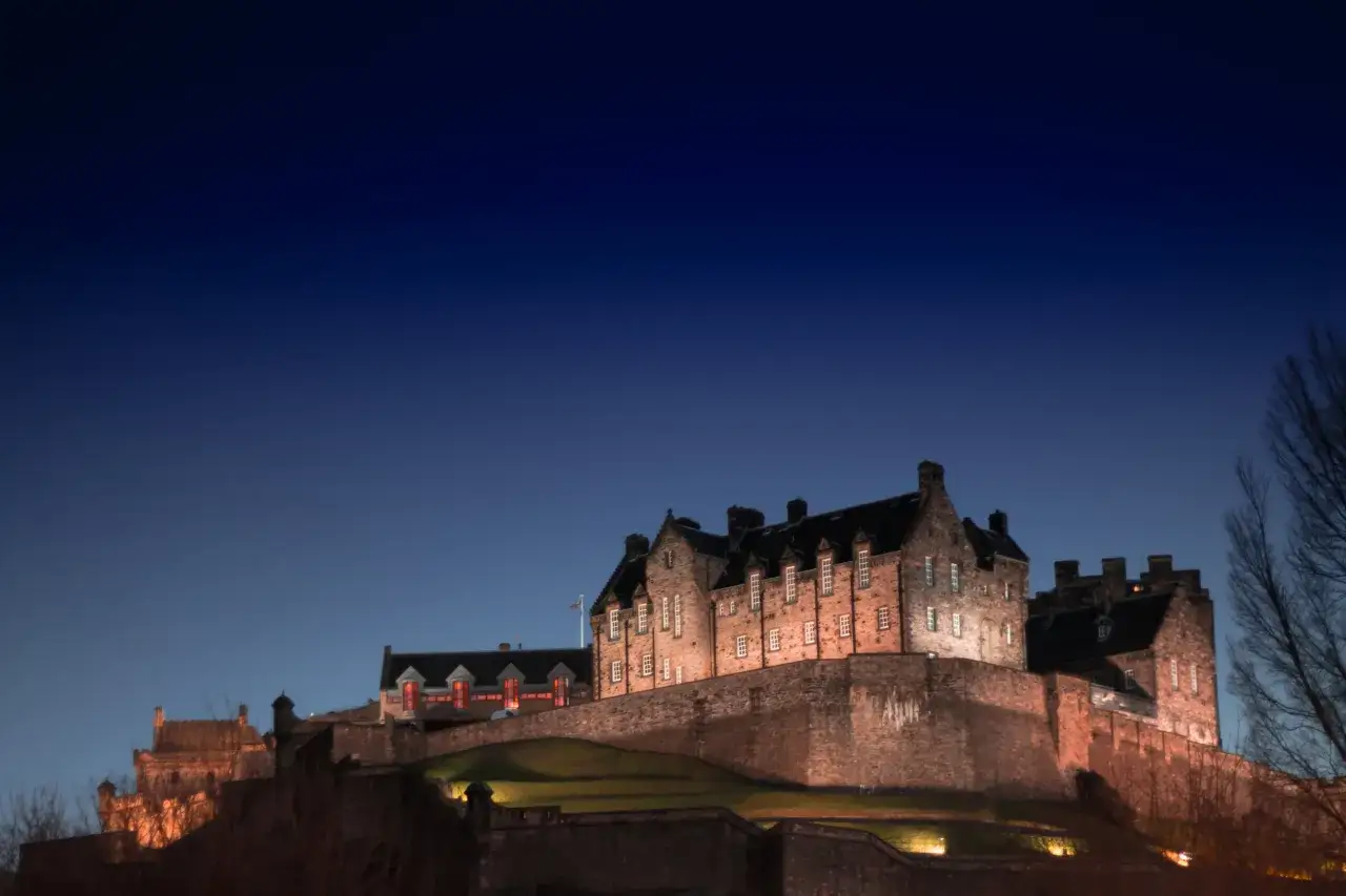 Castillo de Edimburgo iluminado al anochecer, un lugar mágico para visitar con niños y crear recuerdos inolvidables.