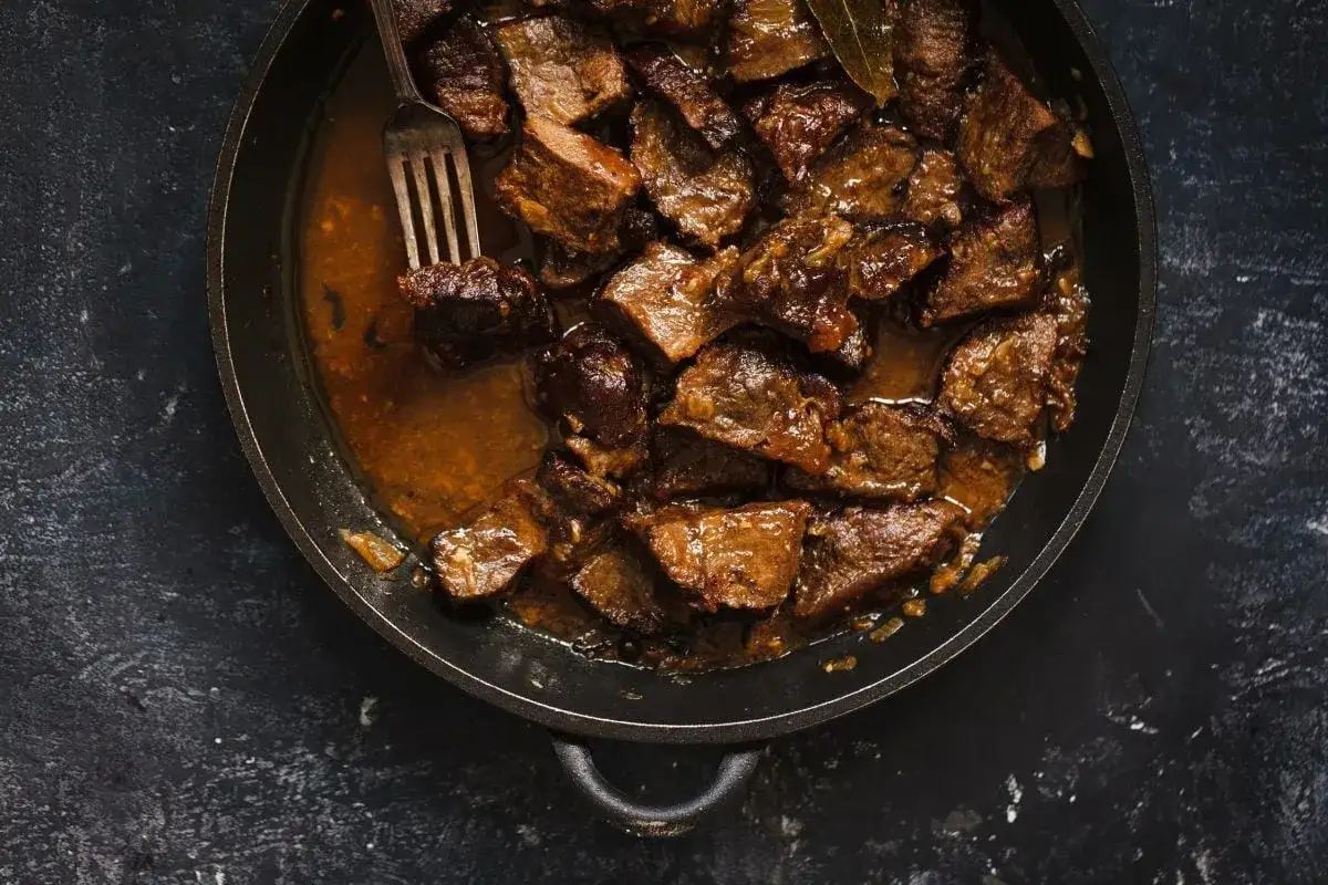 Un plat mijoté de daube de boeuf, avec des morceaux tendres dans une sauce riche, une fourchette prête à servir.