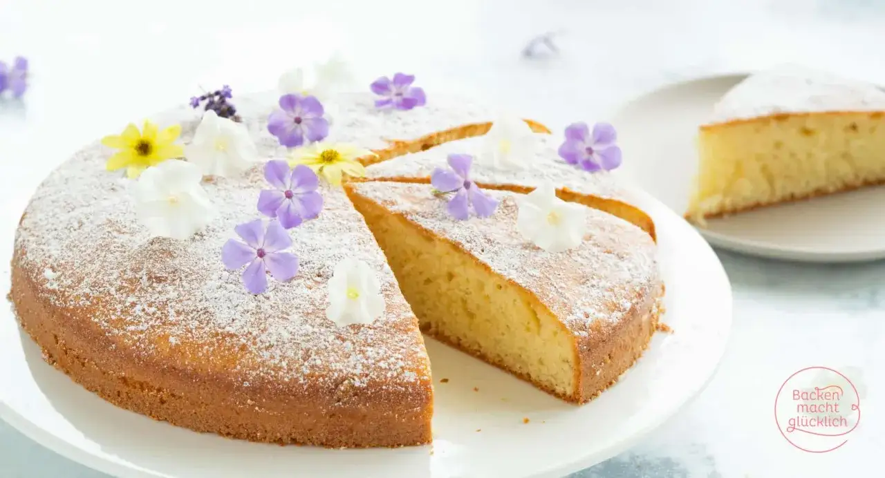 Saftiger Becherkuchen mit Joghurt, bestäubt mit Puderzucker und verziert mit bunten Blüten. Ein einfaches Rezept für süße Momente.
