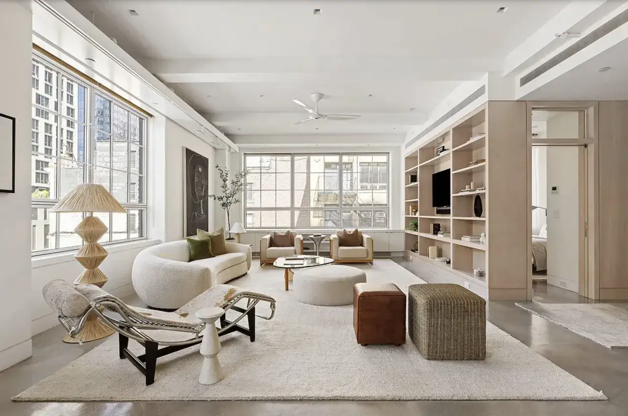 Salón moderno con sofá curvo, sillones, mesa de centro y estanterías. Un espacio lleno de inspiracion decoracion y luz natural.