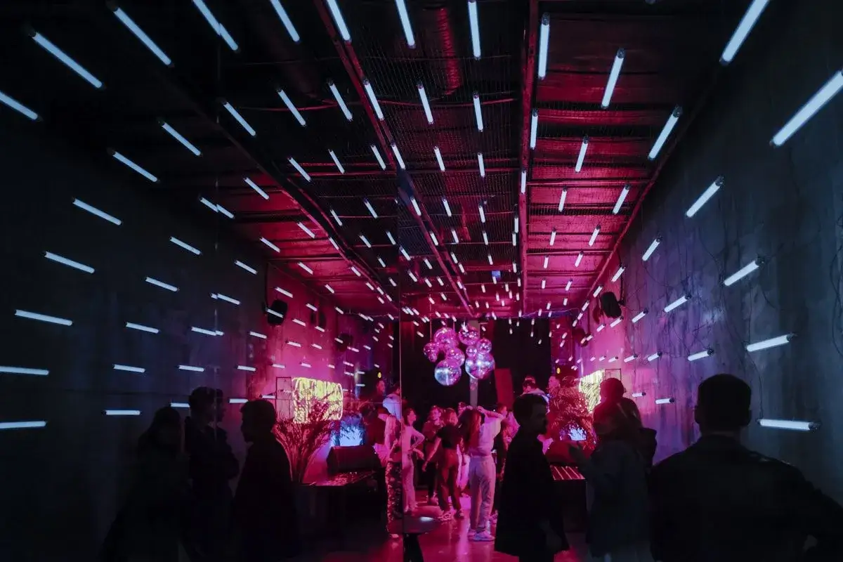 Persone ballano in una discoteca famosa di Barcellona, illuminata da centinaia di tubi al neon bianchi e rosa.