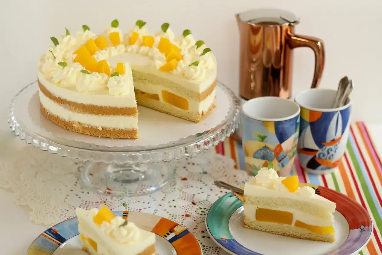 Eine köstliche Quark Sahne Torte mit Mango-Füllung, dekoriert mit Sahnetupfern und Mangostücken. Perfekt für einen süßen Genuss.