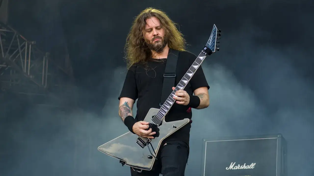 Charyzmatyczny gitarzysta rockowy z długimi włosami, grający na czarnej gitarze typu explorer. Jeden z wielu utalentowanych polskich gitarzystów rockowych.