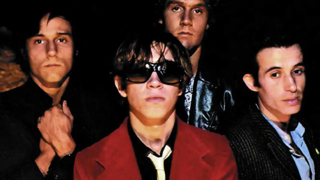 Cuatro hombres con estilo, evocando la energía de la new wave music, posan para una foto.