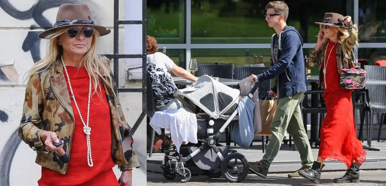 Monika Olejnik w czerwonej sukience i Grzegorz Wasowski spacerują z wózkiem.