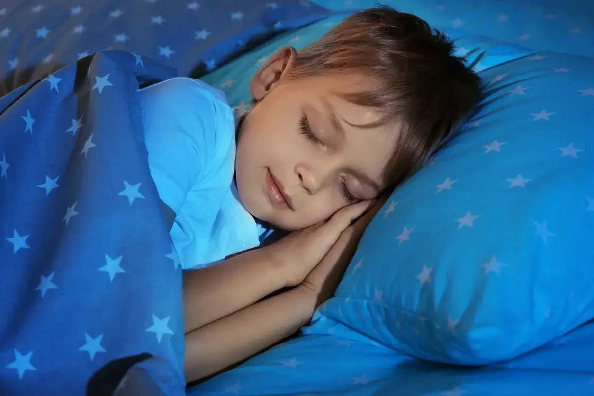 Ni&ntilde;o duerme pl&aacute;cidamente, con su manta de estrellas. Un secreto para saber como dormir a un ni&ntilde;o de 2 a&ntilde;os hiperactivo.