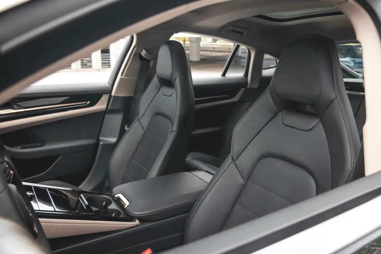 Wnętrze Porsche Panamera 2024: czarne, skórzane fotele, elegancka konsola środkowa i panoramiczny dach.