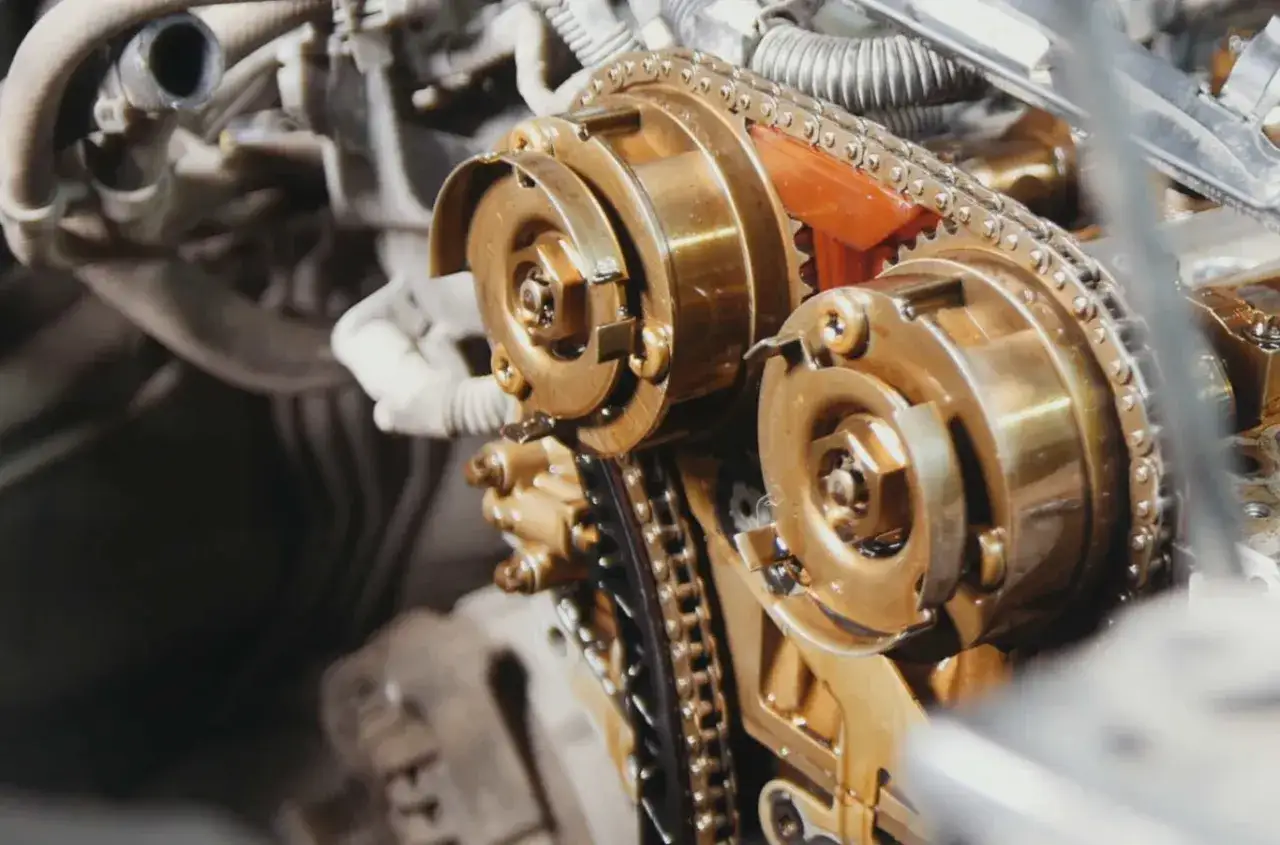 Zbliżenie na mechanizm rozrządu silnika samochodowego. Widoczne koła zębate i łańcuch. Luźny pasek rozrządu objawy mogą prowadzić do uszkodzenia.