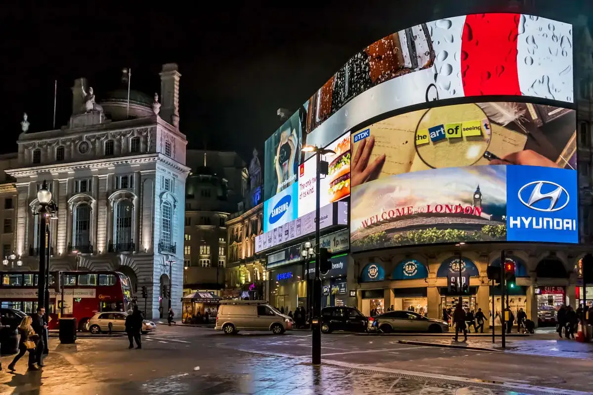 Piccadilly Circus i London p&aring; natten, med blinkande reklamskyltar och en r&ouml;d dubbeld&auml;ckare. En livlig plats som p&aring;minner om nattklubbar i London.