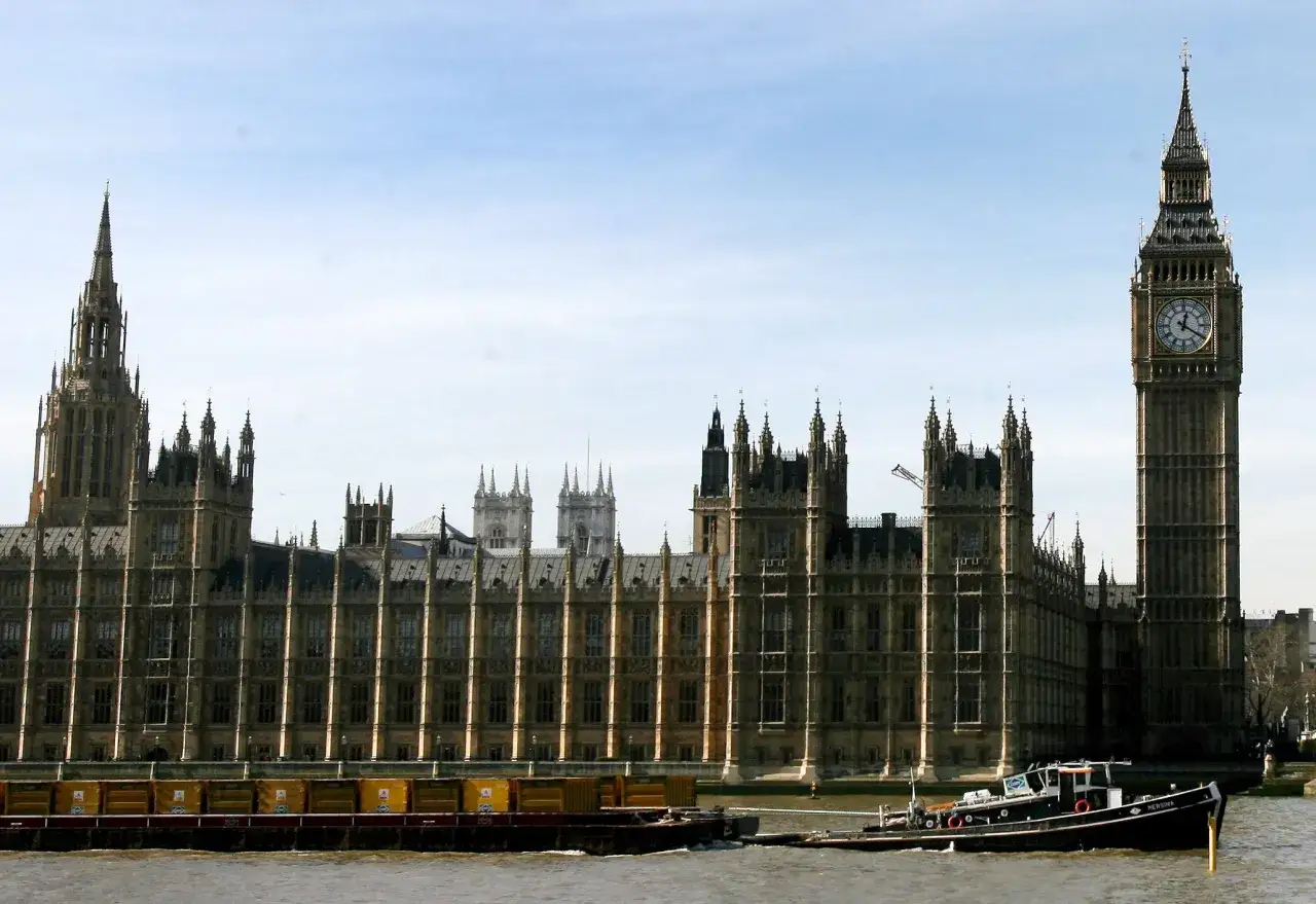 El ic&oacute;nico reloj Big Ben se alza junto al Palacio de Westminster, con barcazas navegando por el r&iacute;o T&aacute;mesis.