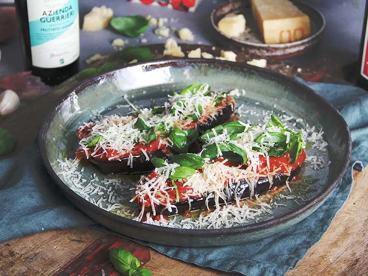 Aubergine i ugn, toppad med tomatsås, basilika och rikligt med riven ost. En härlig italiensk rätt som doftar ljuvligt.