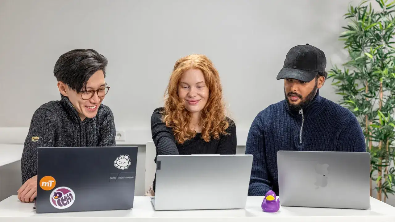 Tre personer jobbar vid varsin laptop. En data scientist ler vid sin sk&auml;rm.