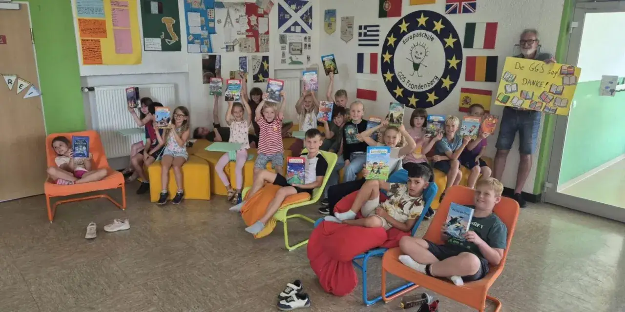 Kinder der Europaschule Fr&ouml;ndenberg zeigen stolz ihre B&uuml;cher. Ein Lehrer h&auml;lt ein Dankesch&ouml;n-Schild. F&ouml;rderung der **Basiskompetenzen Grundschule** durch Lesen.