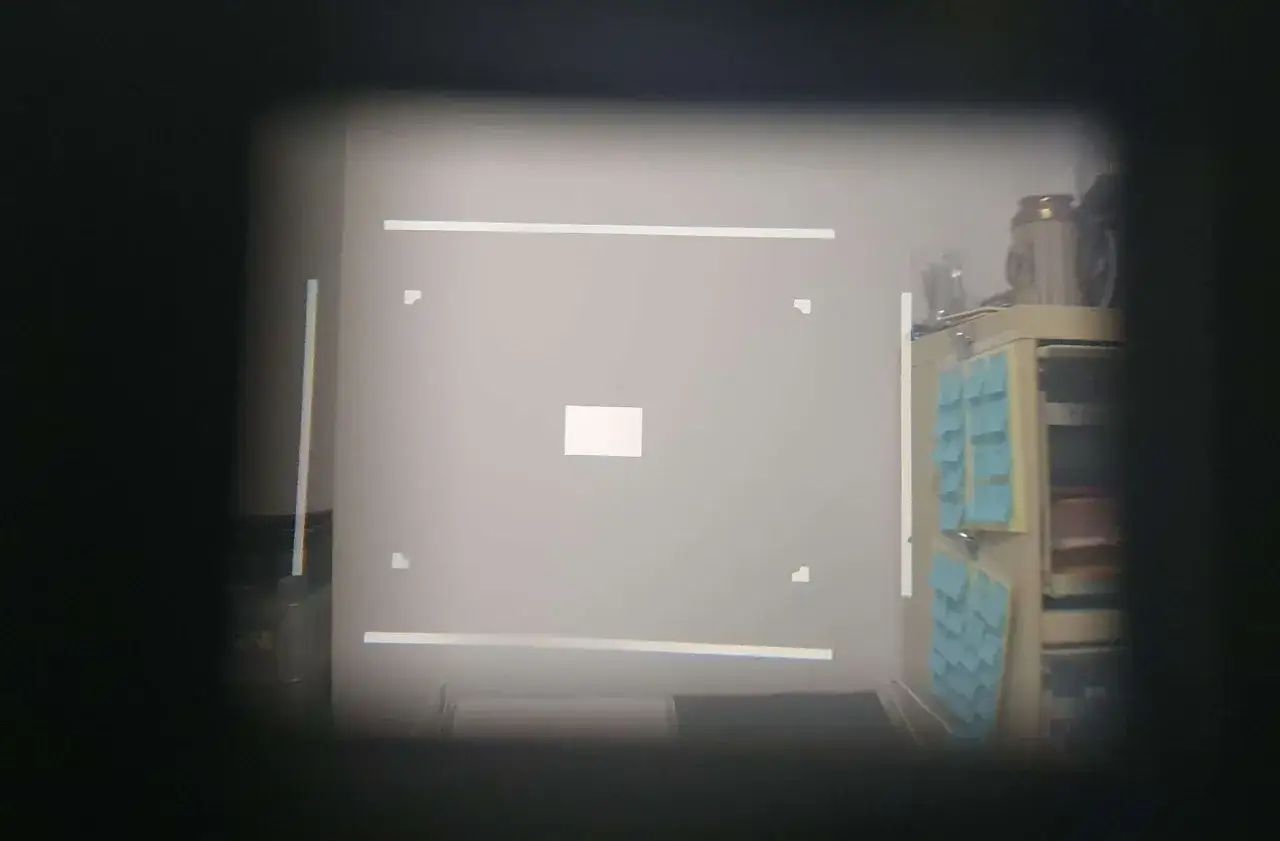 Viewfinder of a Leica M4 showing framelines. A white square is centered, with corner markers and horizontal lines.