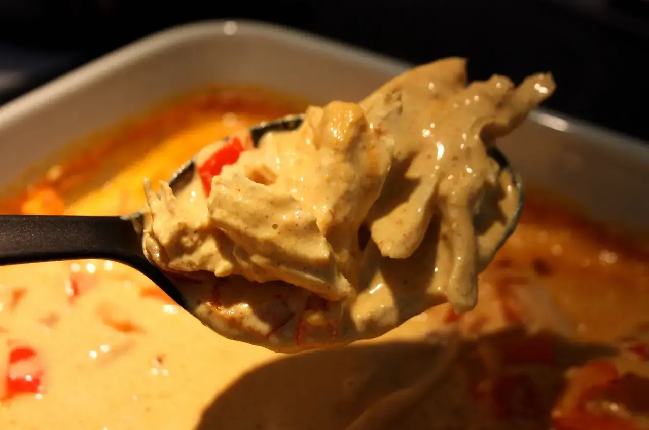 En sked med krämig kyckling i en gyllene mango chutney sås.