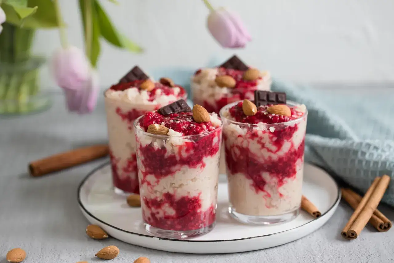 Vier Gl&auml;ser mit Milchreis mit Vanillepudding, Himbeeren, Mandeln und Schokolade. Ein s&uuml;&szlig;er Genuss!