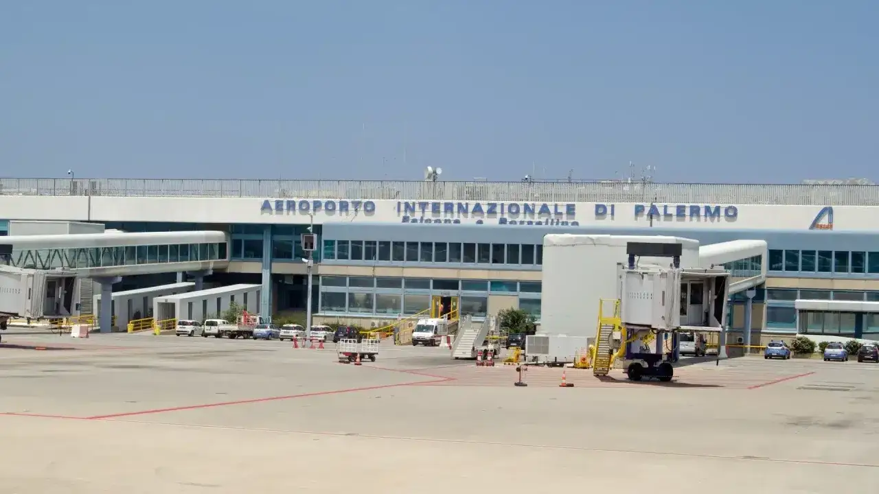 Flygplanet är parkerat vid Aeroporto Internazionale di Palermo. En jetbrygga leder till terminalen.