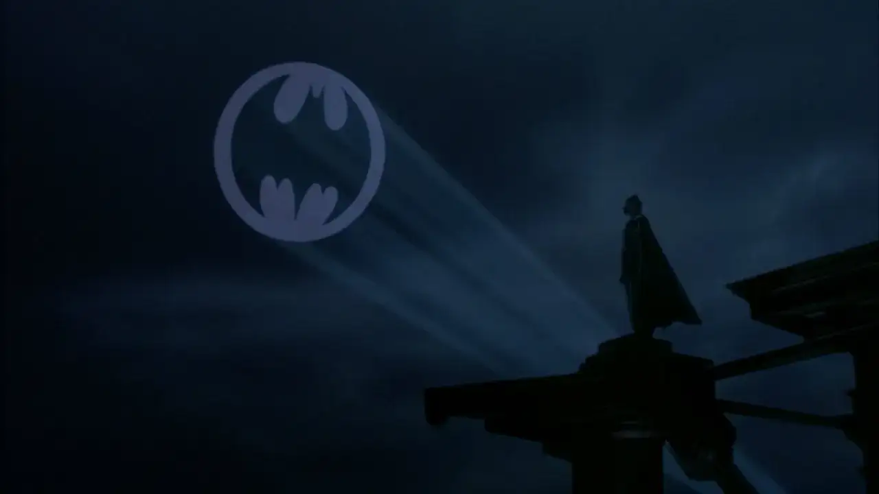 Mroczny **batman znak na niebie** rozświetla noc. Na dachu budynku stoi samotna postać w pelerynie, gotowa do akcji.