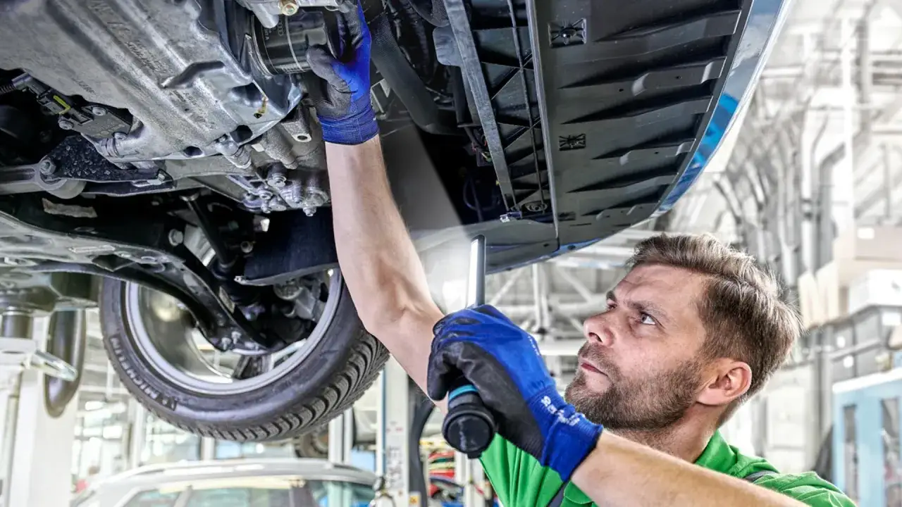 Mechanik w serwisie VW sprawdza podwozie auta. Zastanawiasz się, ile kosztuje wymiana oleju w serwisie VW?