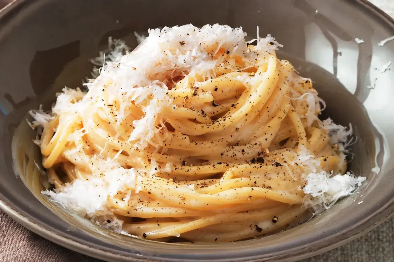 Un piatto di strangozzi cacio e pepe, cremosi e ricchi di pecorino e pepe nero macinato fresco.