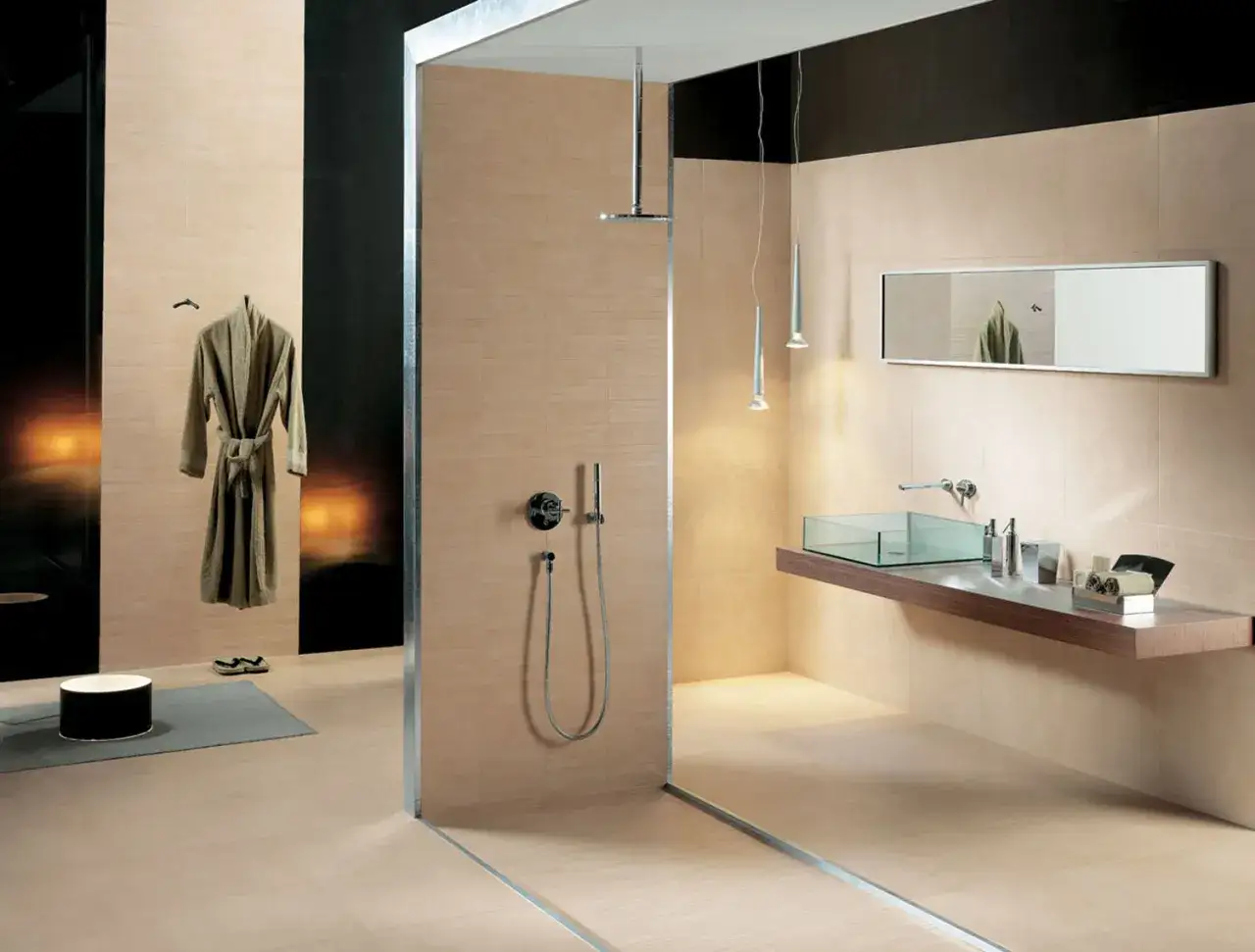 Salle de bain moderne avec douche vitr&eacute;e, lavabo en verre, miroir et peignoir suspendu. Carrelage beige respectant la norme PEI.