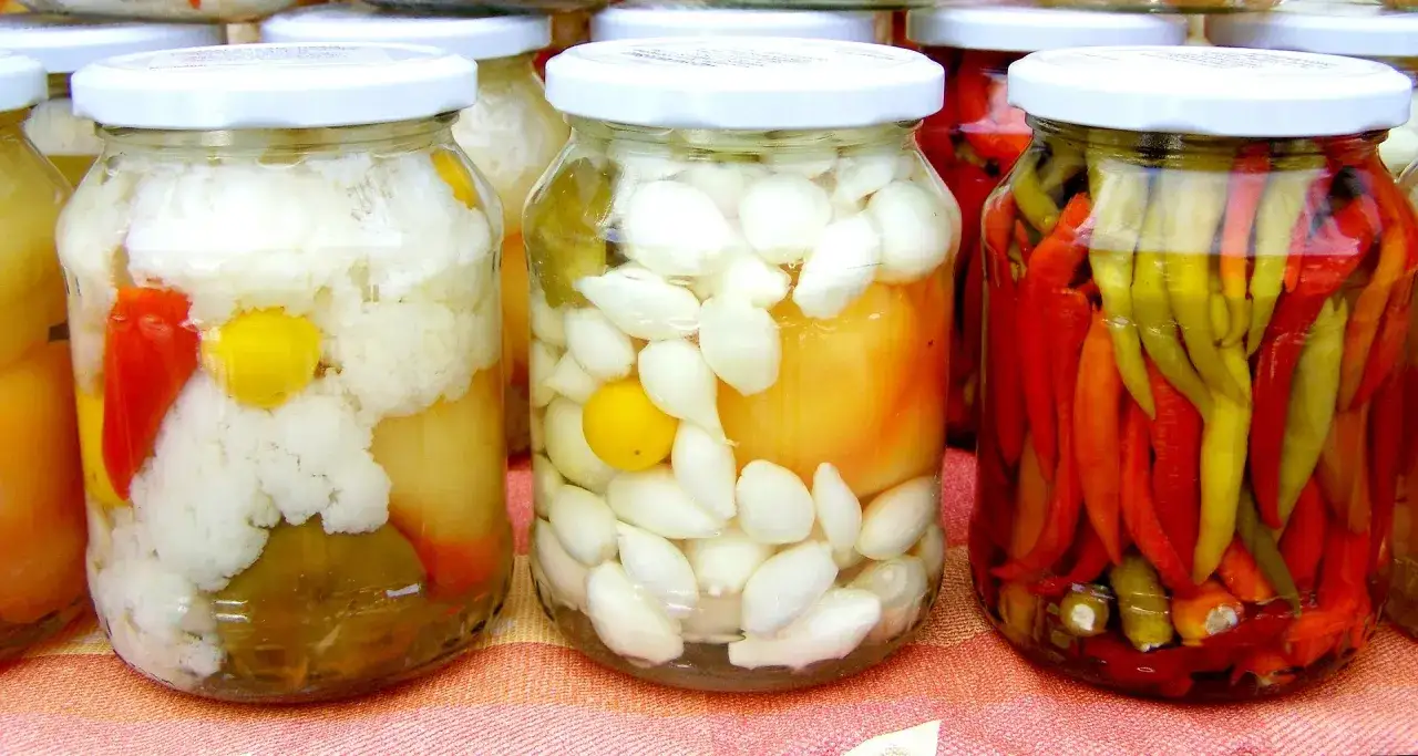 Vasi di giardiniera fatta in casa: cavolfiore, cipolline e peperoncini colorati, pronti per essere gustati.