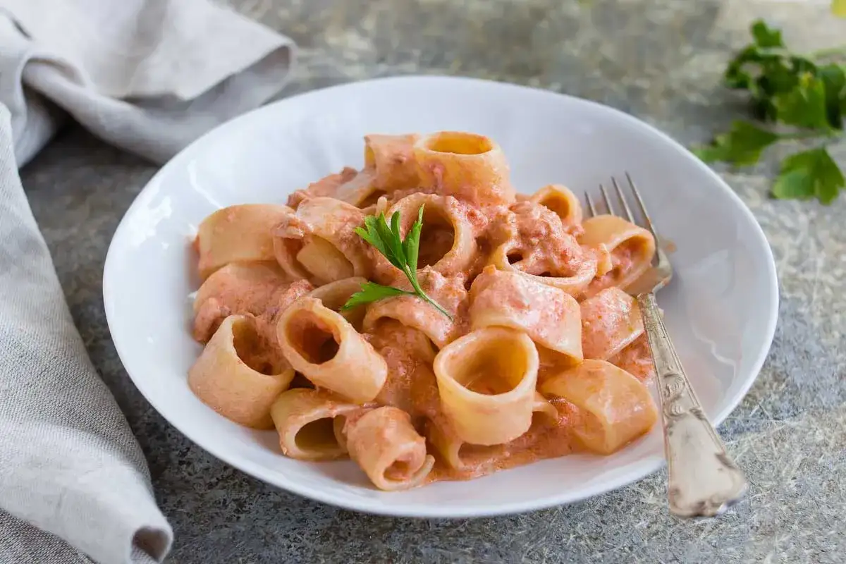 Piatto di pasta con tonno in scatola, condita con una cremosa salsa rosa e guarnita con prezzemolo.