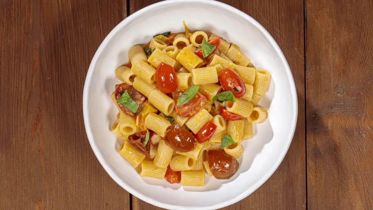 Un piatto di rigatoni conditi con succosi pomodorini, basilico fresco e un filo d'olio. Un classico della cucina italiana.