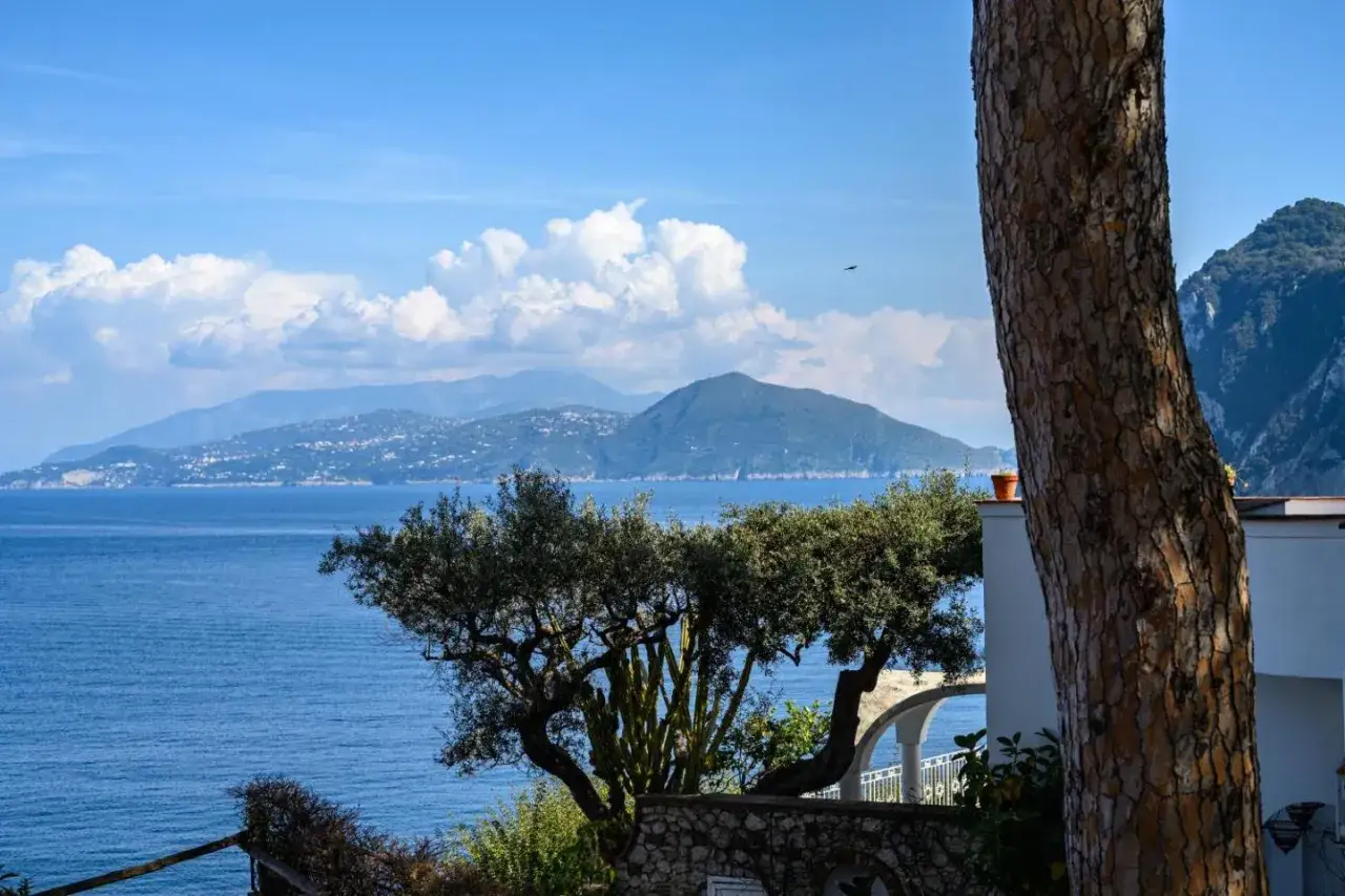 Widok na morze z Capri, idealne miejsce na wczasy all inclusive. Piękne góry w tle i błękitne niebo.