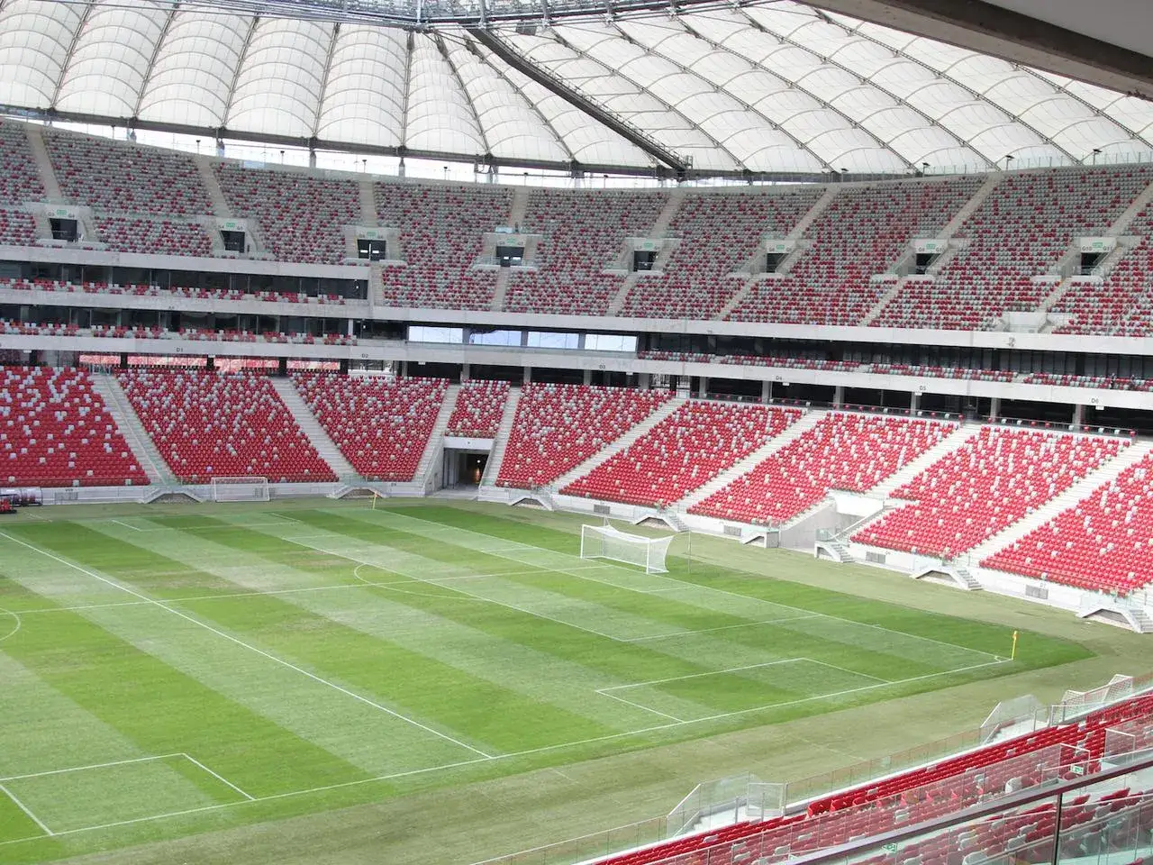 Pusta trybuna stadionu narodowego ile miejsc? Widok na murawę i czerwono-szare siedzenia dla tysięcy kibiców.