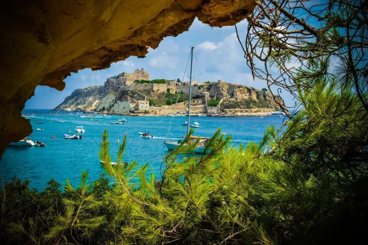 Vista incantevole delle Isole Tremiti: cosa vedere? Un castello domina l'isola, circondata da acque cristalline e barche.