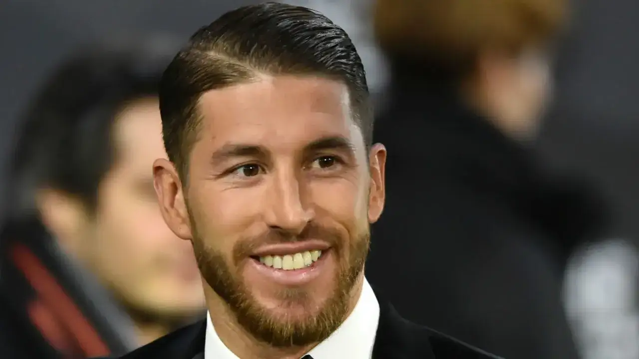 Sergio Ramos z charakterystycznym przedziałkiem z boku, uśmiecha się szeroko, prezentując swoją zadbaną brodę.
