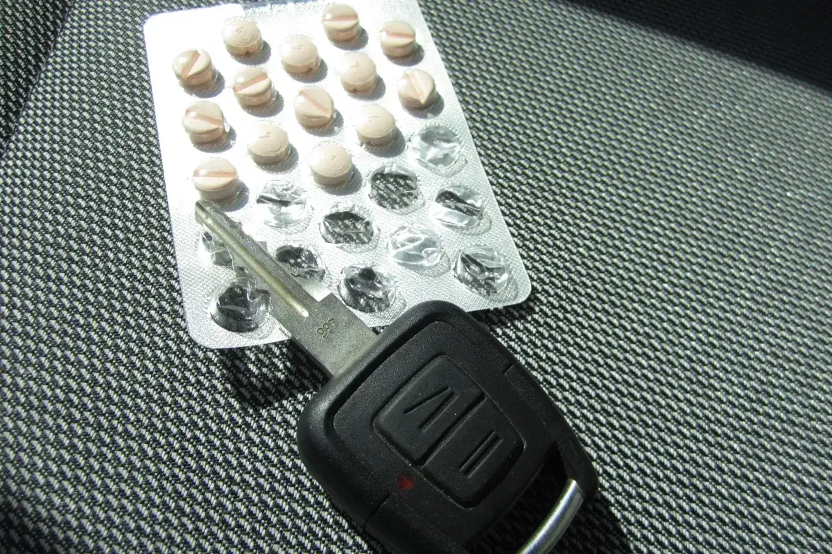 Tabletten und Autoschl&uuml;ssel liegen nebeneinander. Tilidin autofahren ist gef&auml;hrlich und illegal.