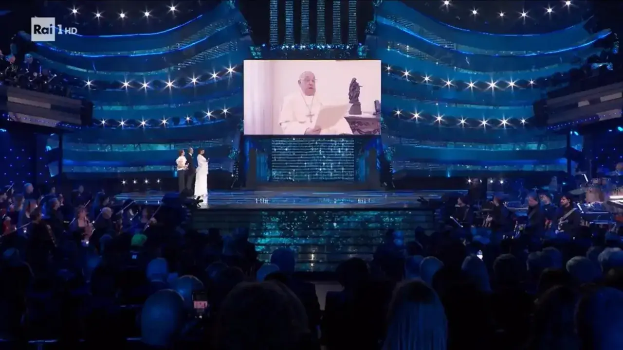Pope Francis appears on screen at the San Remo Festival, addressing a live audience and orchestra.