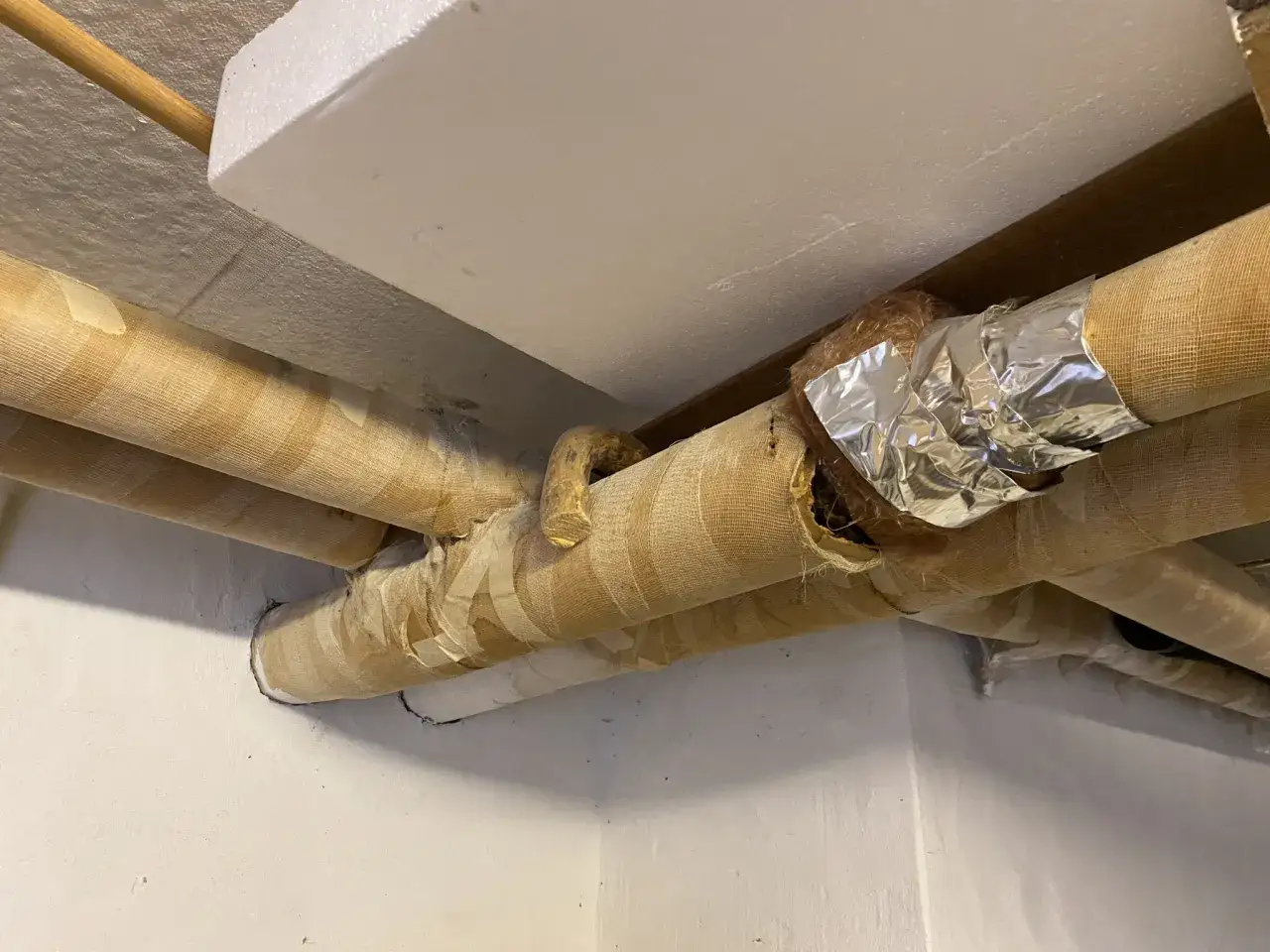 Rör med gammal asbestisolering, delvis täckt med tejp och aluminiumfolie.