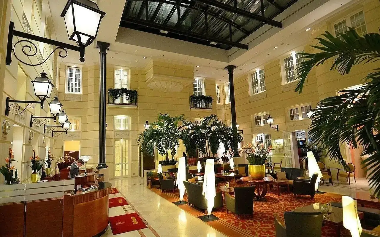 Eleganckie lobby hotelowe z palmami i recepcją. Zastanawiasz się, ile zarabia manager hotelu w takim miejscu?