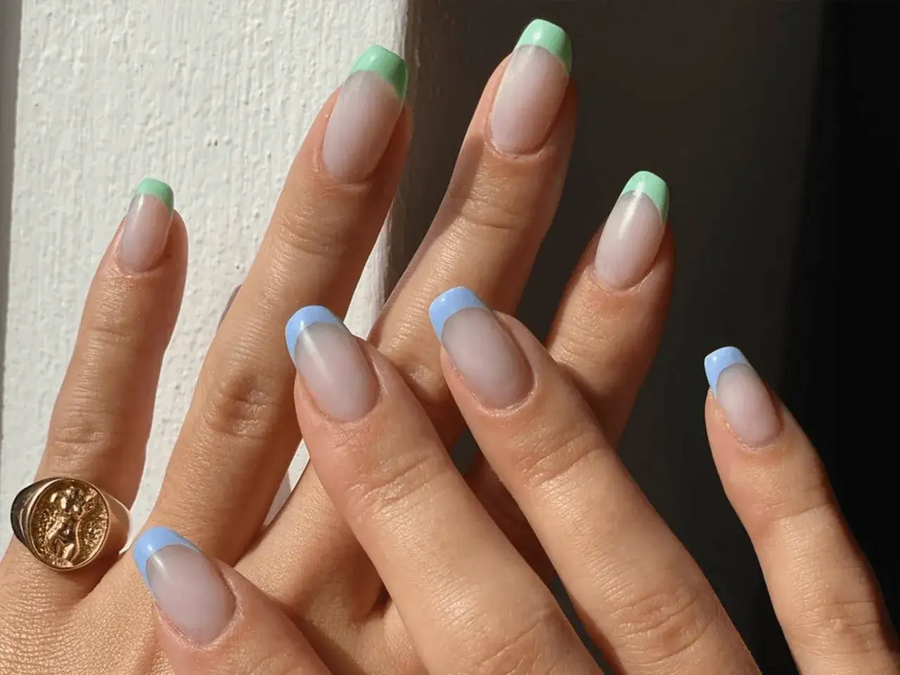 Unghie corte con french manicure colorata: punte verdi e azzurre su base trasparente. Un look fresco e moderno.
