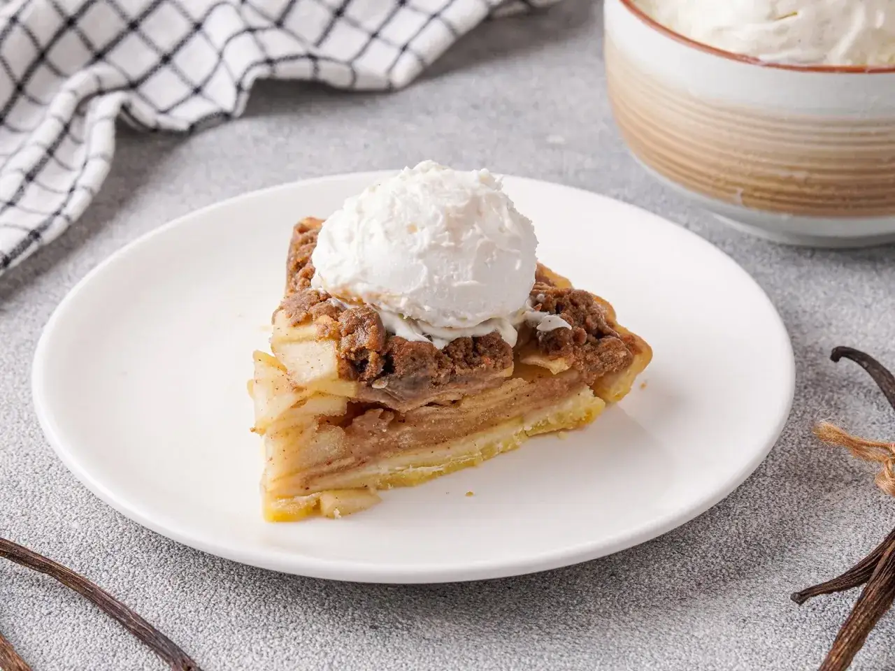 Ein St&uuml;ck Apfelkuchen mit einer Kugel cremigem Eis mit Milch statt Sahne, garniert mit Zimt und Vanille.