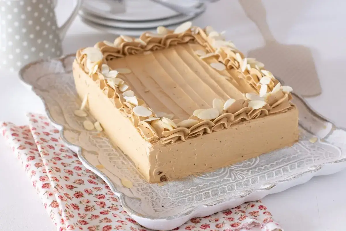 Tarta de moka rectangular, cubierta con crema de caf&eacute; y almendras laminadas. Decorada con un borde de crema rizada.