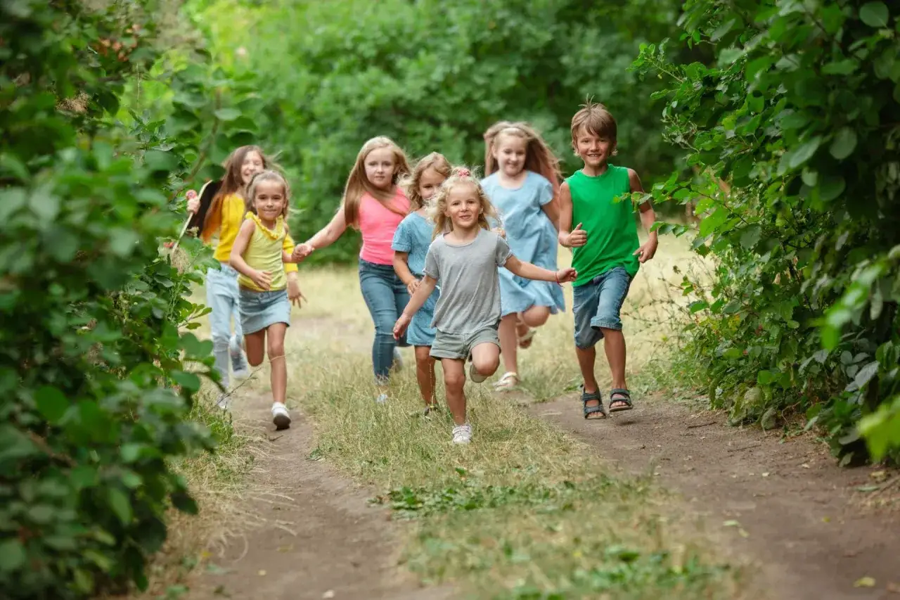 Kinder genießen ihre Sommerferien in Bremen und rennen lachend durch einen grünen Waldweg.