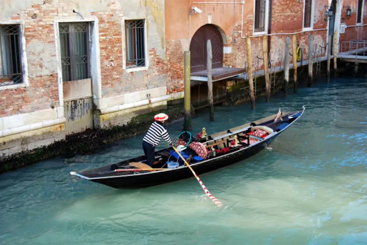 Gondola veneziana con gondoliere, un mezzo di trasporto unico, a differenza di un sandalo che si indossa ai piedi.