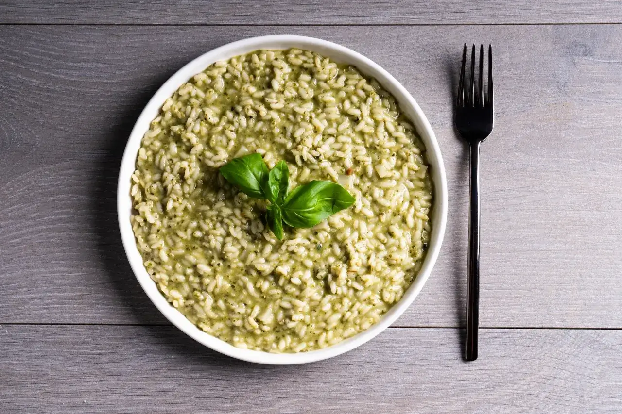 Risotto z bazylią, klasyk kuchni włoskiej, podane w białej misce z widelcem obok.